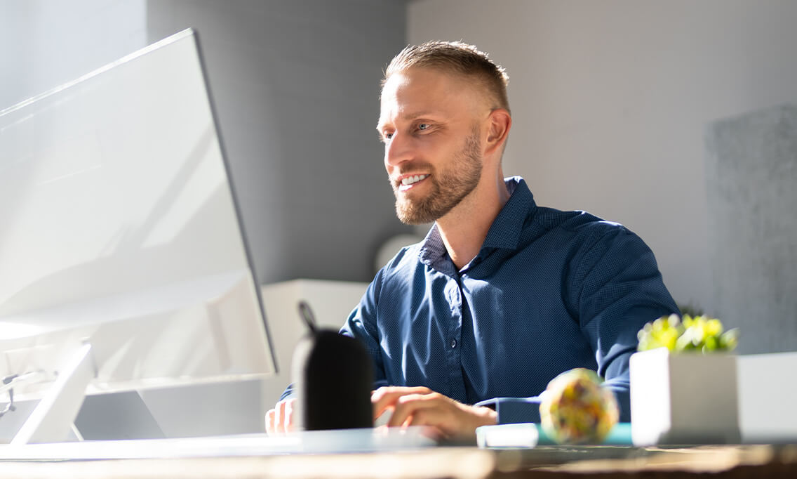 Mann im blauen Hemd am modernen Schreibtisch mit großem Monitor – Header der Webinarseite von der Schildknecht AG.